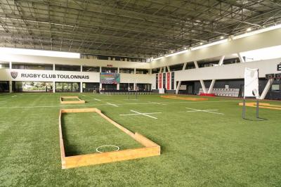 Table ronde en bois entourée de chaises à motifs rouges et blancs, située dans un jardin avec des plantes et des fleurs.