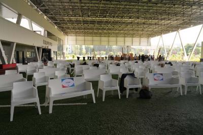 Table ronde en bois entourée de chaises à motifs rouges et blancs, située dans un jardin avec des plantes et des fleurs.