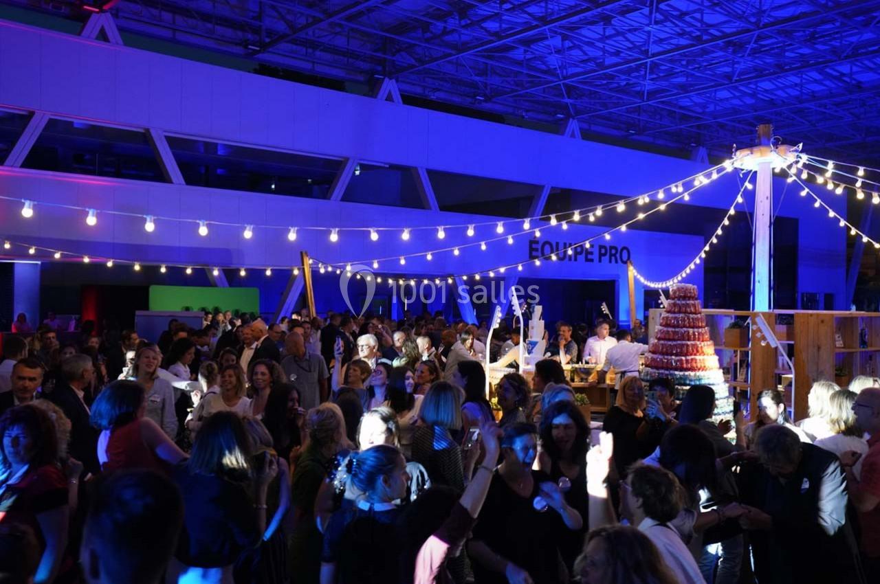 Foule dans un espace intérieur décoré de guirlandes lumineuses, participant à un événement festif en soirée.