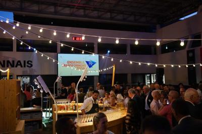 Table ronde en bois entourée de chaises à motifs rouges et blancs, située dans un jardin avec des plantes et des fleurs.