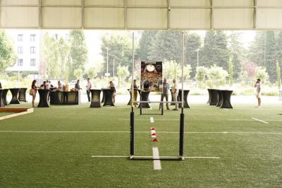 Table ronde en bois entourée de chaises à motifs rouges et blancs, située dans un jardin avec des plantes et des fleurs.