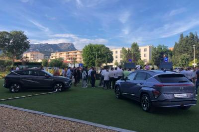 Table ronde en bois entourée de chaises à motifs rouges et blancs, située dans un jardin avec des plantes et des fleurs.