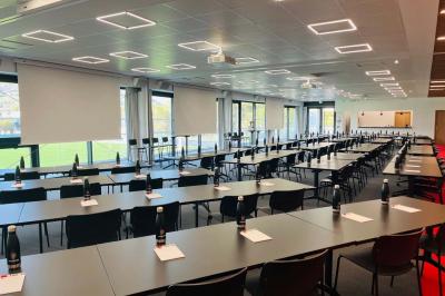 Table ronde en bois entourée de chaises à motifs rouges et blancs, située dans un jardin avec des plantes et des fleurs.