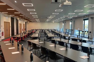 Table ronde en bois entourée de chaises à motifs rouges et blancs, située dans un jardin avec des plantes et des fleurs.