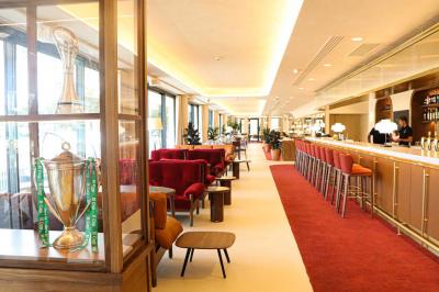 Table ronde en bois entourée de chaises à motifs rouges et blancs, située dans un jardin avec des plantes et des fleurs.