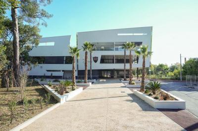 Table ronde en bois entourée de chaises à motifs rouges et blancs, située dans un jardin avec des plantes et des fleurs.