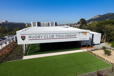 Table ronde en bois entourée de chaises à motifs rouges et blancs, située dans un jardin avec des plantes et des fleurs.