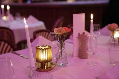 Table ronde en bois entourée de chaises à motifs rouges et blancs, située dans un jardin avec des plantes et des fleurs.