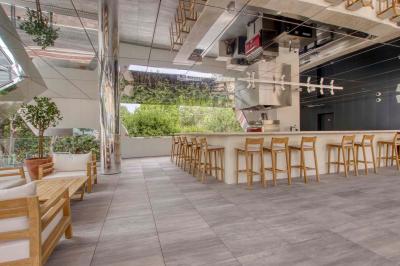 Table ronde en bois entourée de chaises à motifs rouges et blancs, située dans un jardin avec des plantes et des fleurs.