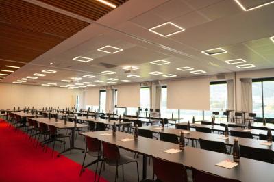 Table ronde en bois entourée de chaises à motifs rouges et blancs, située dans un jardin avec des plantes et des fleurs.