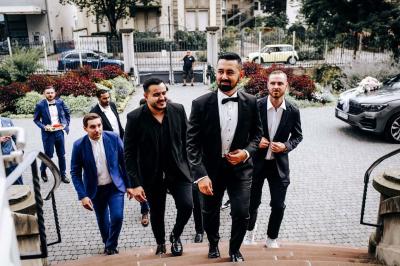 Un couple en tenue de mariage se tient sur un ponton en bois devant un lac entouré d'arbres.