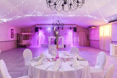 Un couple de mariés danse au centre d'une salle entourée d'invités, avec un sol recouvert de fumée légère.