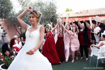 Un couple de mariés danse au centre d'une salle entourée d'invités, avec un sol recouvert de fumée légère.