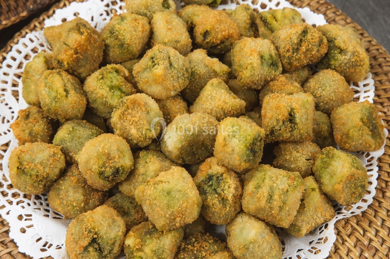 Assortiment de bouchées panées dorées, posées sur une nappe en dentelle blanche.