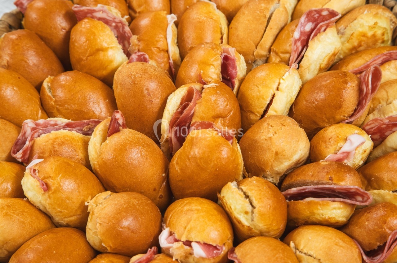 Assortiment de petits pains briochés garnis de tranches de charcuterie.
