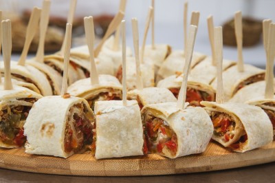 Salle de réception décorée avec des tables rondes dressées, chaises rouges et plafond drapé de voilages lumineux.