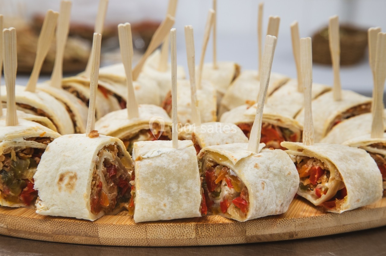 Assortiment de wraps coupés en morceaux, garnis de légumes colorés, présentés avec des piques en bois.