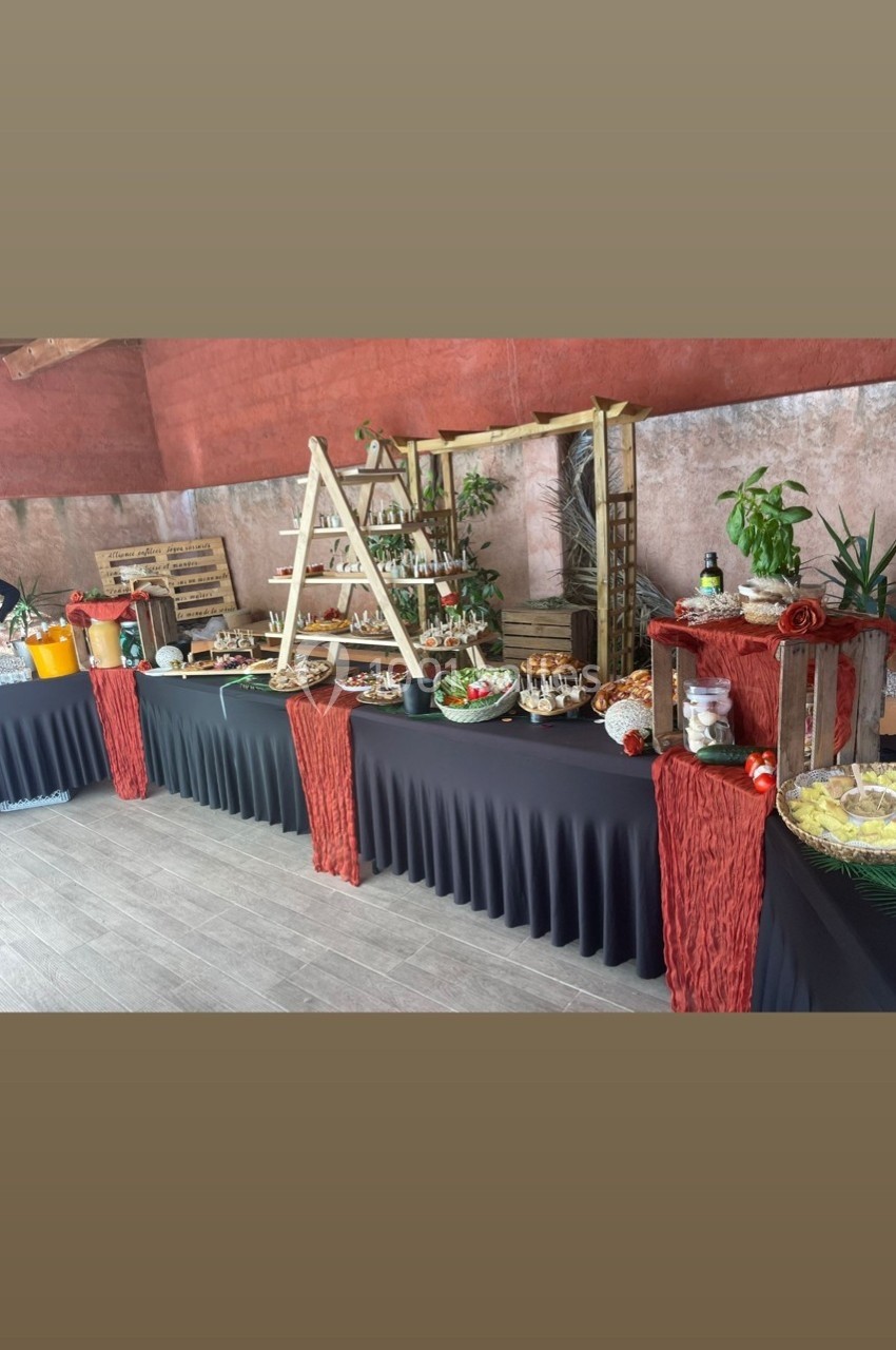 Location salle Cuers (Var) - L'atrium #14 Buffet varié avec plats, boissons et décorations végétales sur des tables drapées de noir dans un espace intérieur.