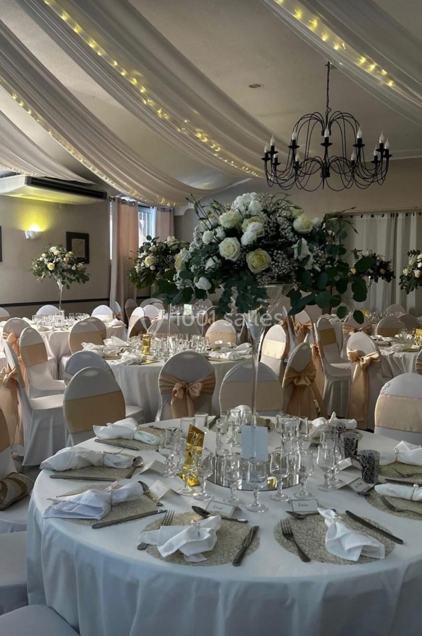 Location salle Cuers (Var) - L'atrium #6 Salle de réception décorée avec des tables rondes, nappes blanches, chaises ornées de nœuds beige et centres de table…
