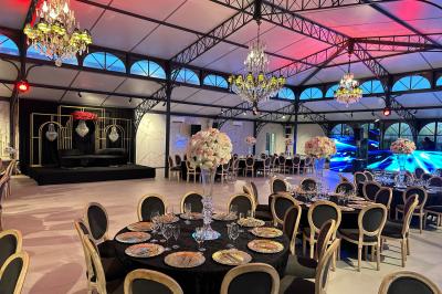 Terrasse extérieure avec tables, chaises, parasol, plantes et vue sur un bâtiment vitré sous un ciel dégagé.