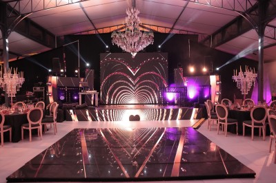 Terrasse extérieure avec tables, chaises, parasol, plantes et vue sur un bâtiment vitré sous un ciel dégagé.