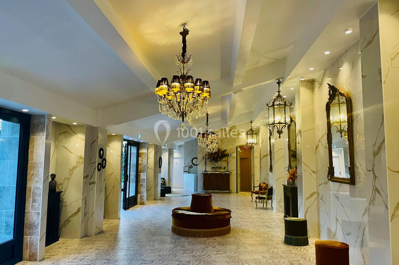 Hall spacieux avec sol en marbre, lustres élégants, miroirs dorés et sièges rembourrés dans un décor lumineux.