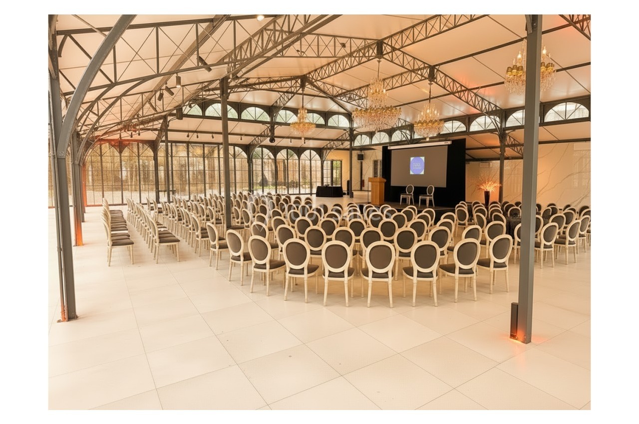 Location salle Bobigny (Seine-Saint-Denis) - Orangerie du Manoir des Vignes #1 Salle de conférence lumineuse avec rangées de chaises alignées face à un écran et une estrade.