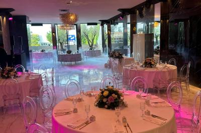 Salon mansardé avec canapé gris, fauteuils, tables d'appoint et éclairage naturel provenant d'une fenêtre inclinée.