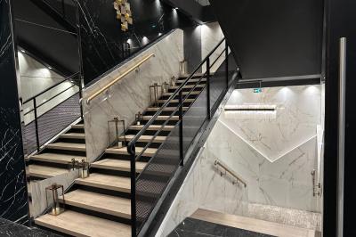 Salon mansardé avec canapé gris, fauteuils, tables d'appoint et éclairage naturel provenant d'une fenêtre inclinée.