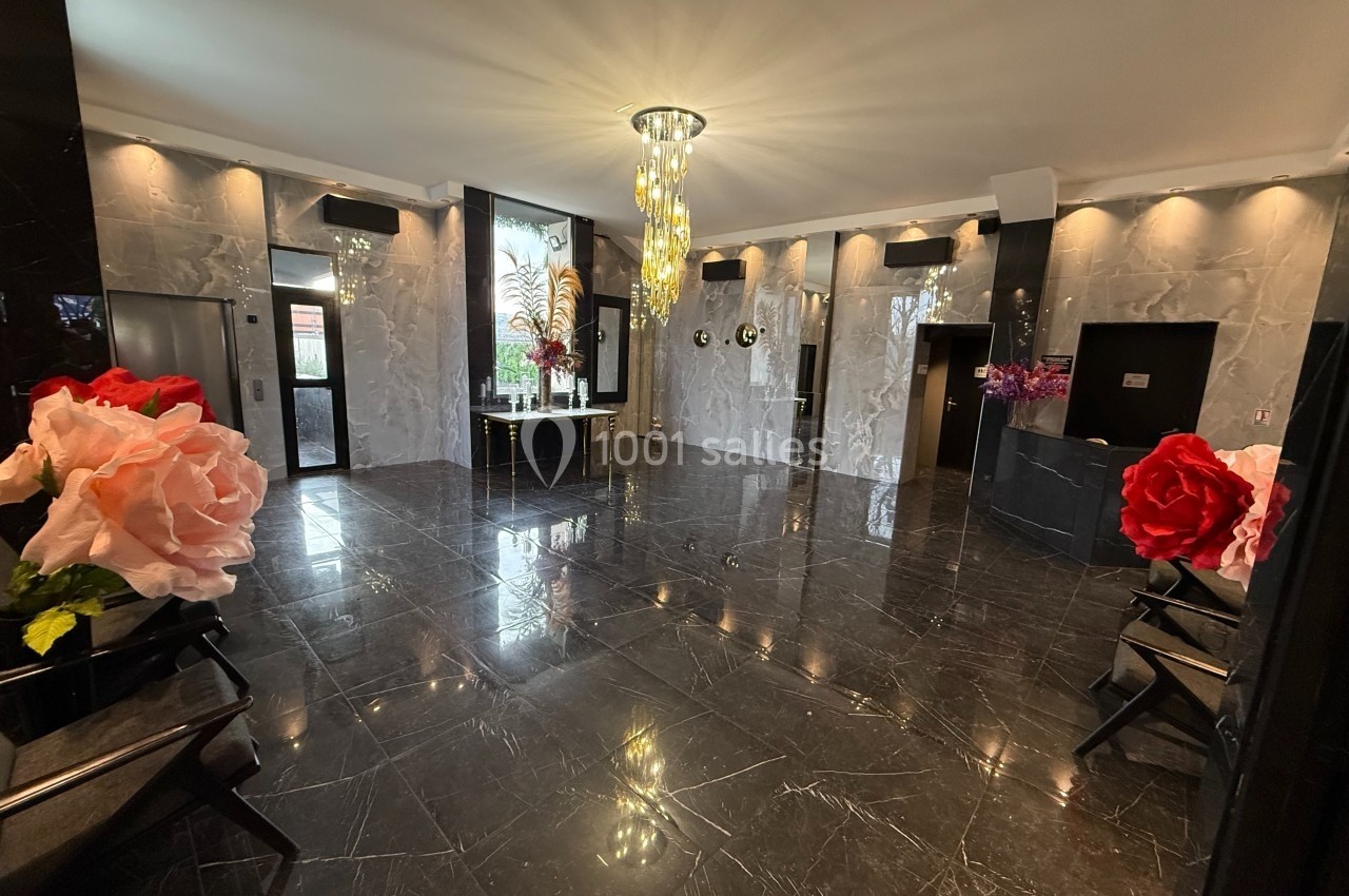 Hall d'entrée élégant avec sol en marbre noir, lustre central lumineux et décorations florales colorées.