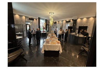 Terrasse ensoleillée aménagée pour un événement, avec tables dressées et parasols rouges.