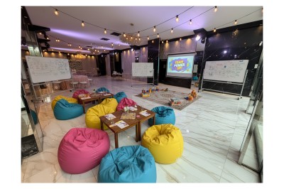 Terrasse ensoleillée aménagée pour un événement, avec tables dressées et parasols rouges.