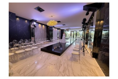 Terrasse ensoleillée aménagée pour un événement, avec tables dressées et parasols rouges.