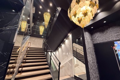 Terrasse ensoleillée aménagée pour un événement, avec tables dressées et parasols rouges.