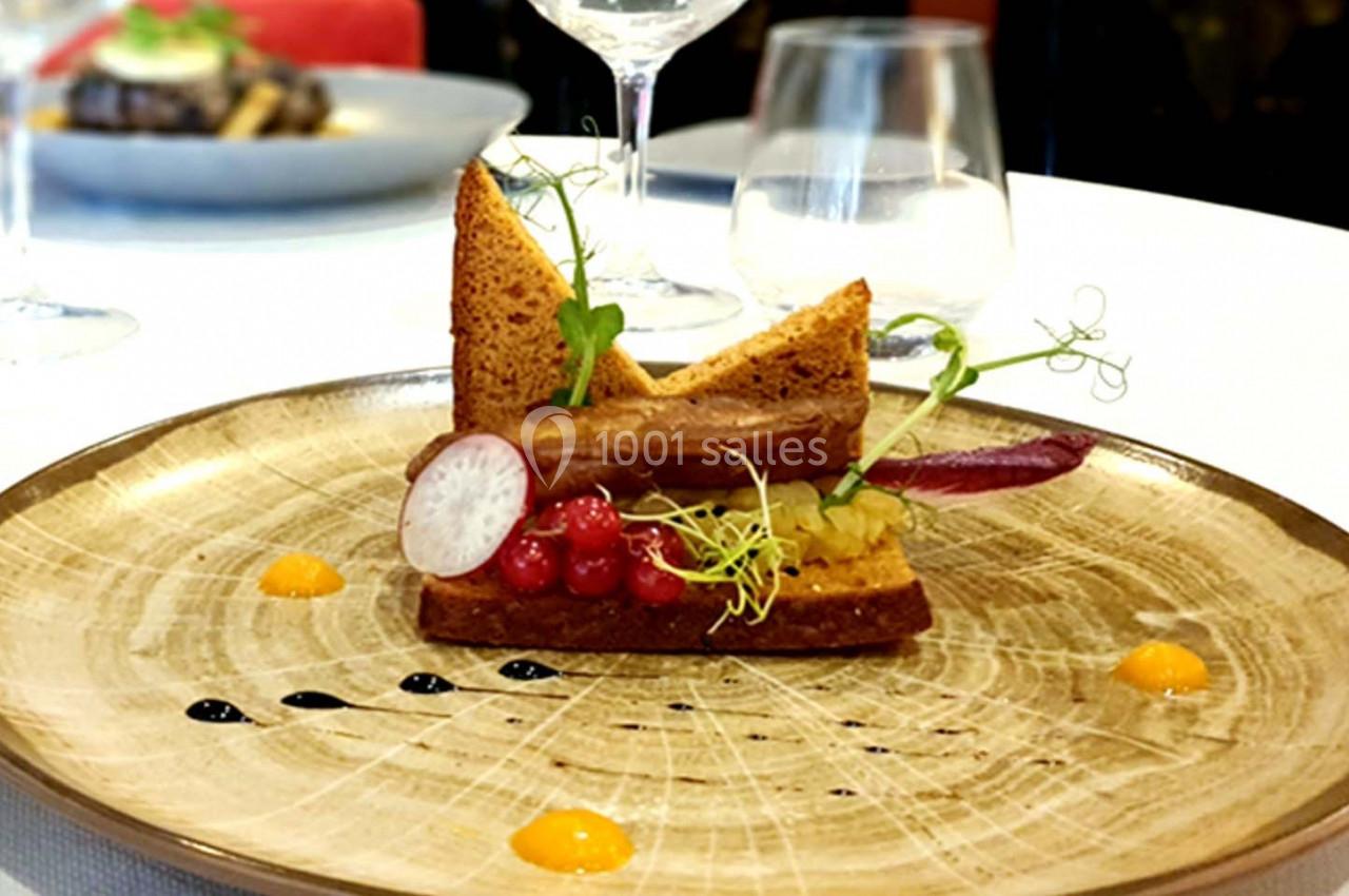 Assiette gastronomique composée de pain grillé, légumes, groseilles et sauces colorées, servie sur une table élégante.