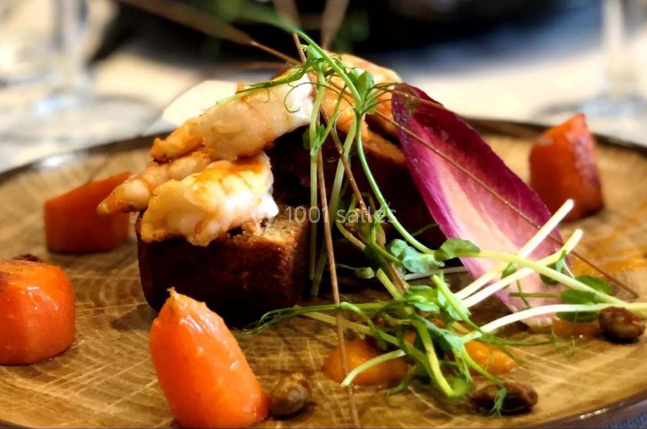 Assiette garnie de langoustines, légumes rôtis, jeunes pousses et endive rouge sur une présentation soignée.
