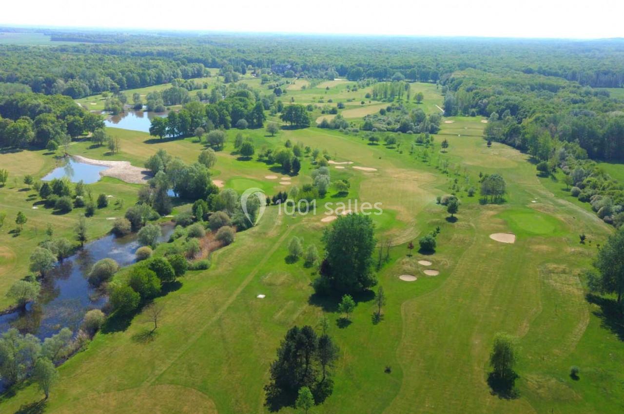 Vue aérienne d'un vaste terrain de golf entouré de forêts, avec des étangs et des espaces verts bien entretenus.