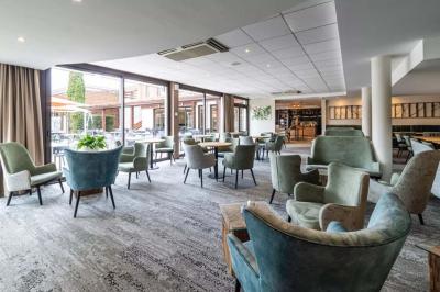 Salle de conférence avec rangées de chaises colorées, un pupitre à l'avant et des panneaux en bois en arrière-plan.