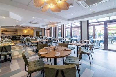 Salle de conférence avec rangées de chaises colorées, un pupitre à l'avant et des panneaux en bois en arrière-plan.