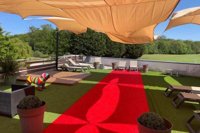 Salle de conférence avec rangées de chaises colorées, un pupitre à l'avant et des panneaux en bois en arrière-plan.