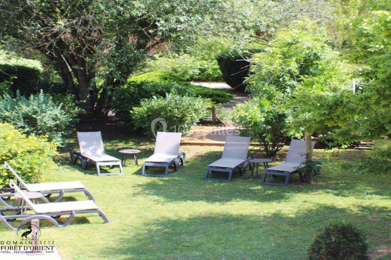 Chaises longues disposées sur une pelouse entourée de végétation luxuriante dans un jardin ensoleillé.