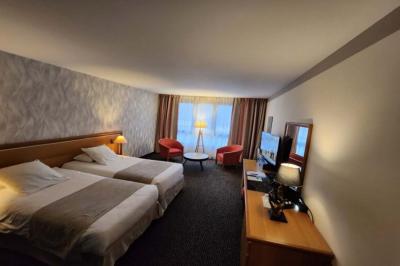 Salle de conférence avec rangées de chaises colorées, un pupitre à l'avant et des panneaux en bois en arrière-plan.