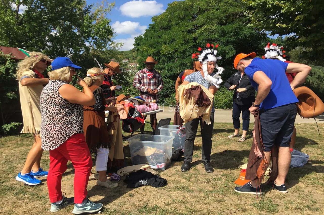 Un groupe de personnes en plein air se prépare en enfilant des costumes de cow-boys et d'Amérindiens.