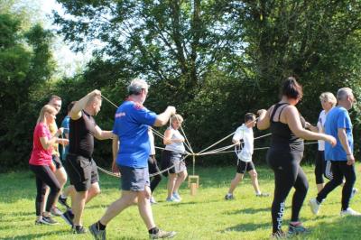 Salle de conférence avec rangées de chaises colorées, un pupitre à l'avant et des panneaux en bois en arrière-plan.