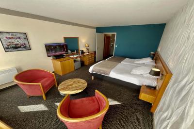 Salle de conférence avec rangées de chaises colorées, un pupitre à l'avant et des panneaux en bois en arrière-plan.