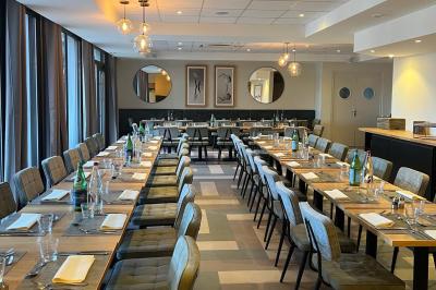 Salle de conférence avec rangées de chaises colorées, un pupitre à l'avant et des panneaux en bois en arrière-plan.