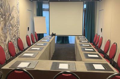 Salle de conférence avec rangées de chaises colorées, un pupitre à l'avant et des panneaux en bois en arrière-plan.