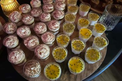 Table garnie de desserts variés, incluant une pièce montée, des verrines et des pâtisseries, dans un cadre tamisé.