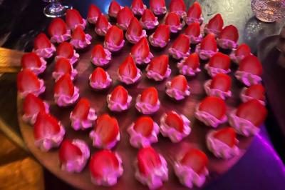 Table garnie de desserts variés, incluant une pièce montée, des verrines et des pâtisseries, dans un cadre tamisé.