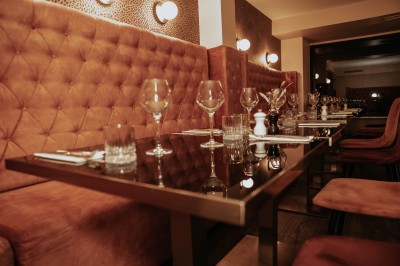 Terrasse extérieure avec tables et chaises noires, entourée de végétation et de bâtiments résidentiels.